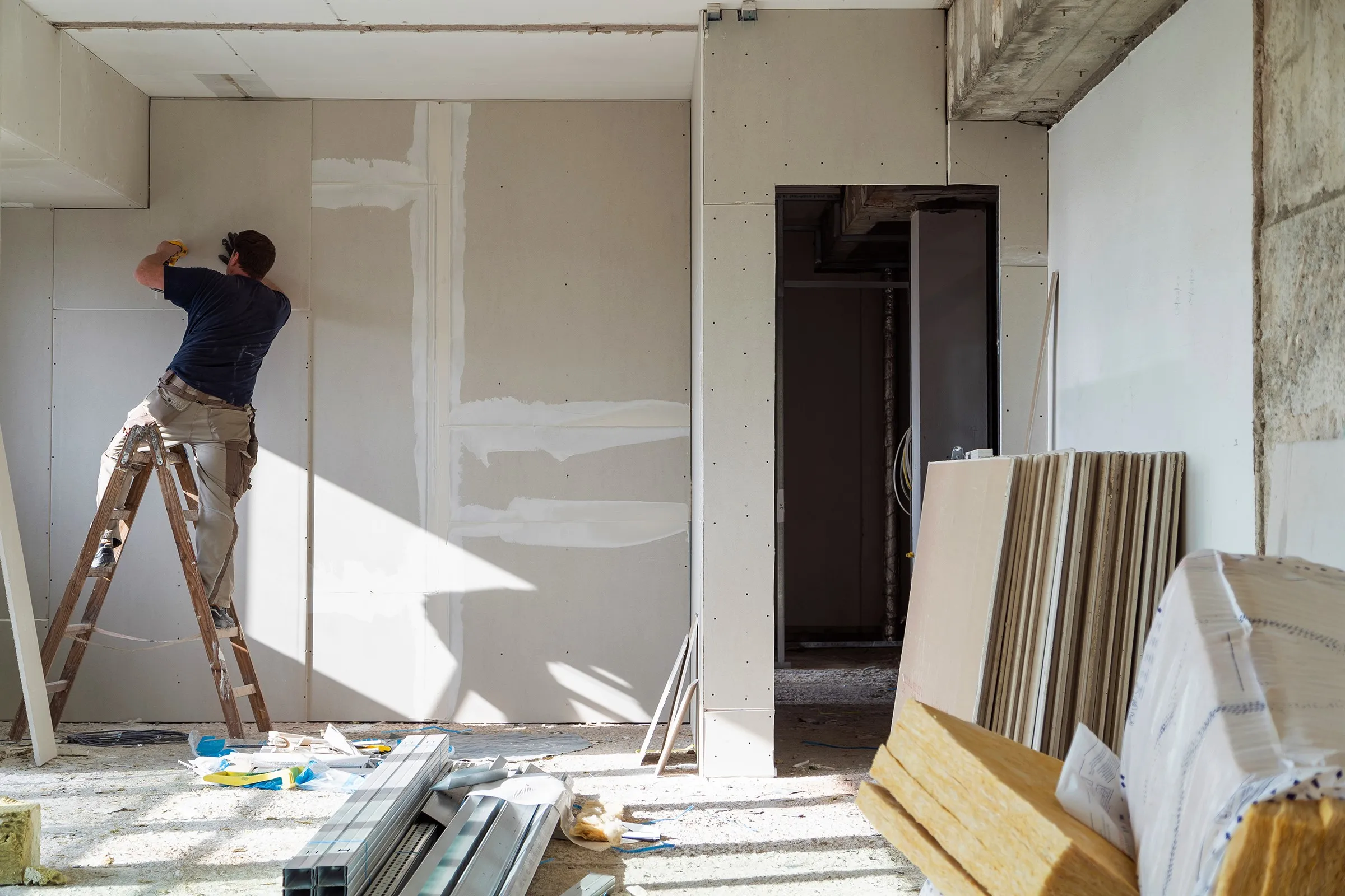 A man standing on a ladder painting a wall